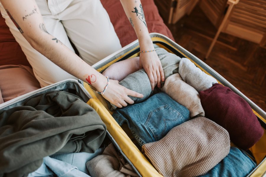 Hands packing a suitcase for travel
