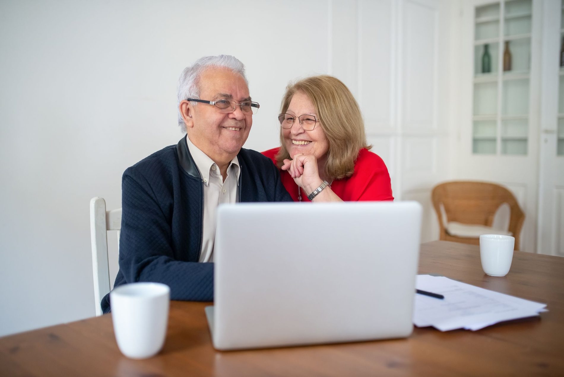 Senior couple smiling together while looking at a laptop